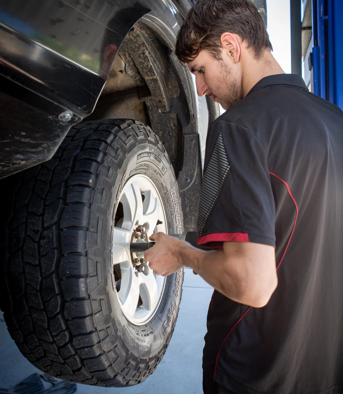 A mechanic tightening the wheel nuts on a 4WD all-terrain tyre