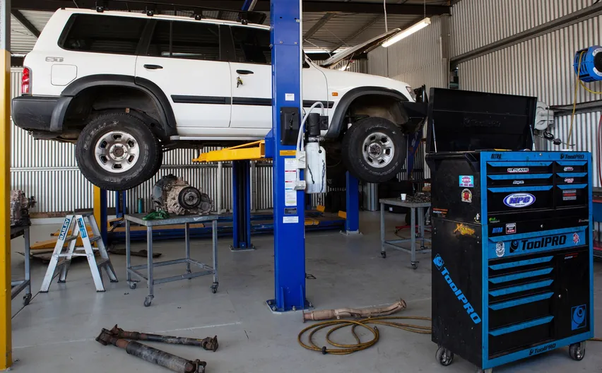 A white 4WD raised on a hoist in the Everything Automotive workshop, with a tool chest and parts on the floor