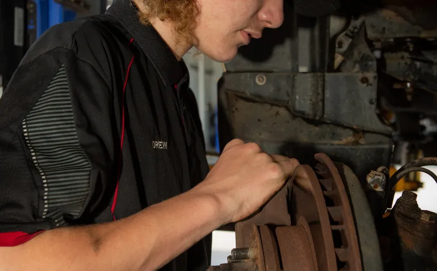 A mechanic working on a brake rotor and hub