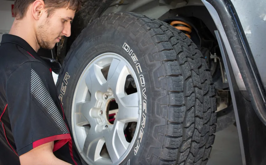 A mechanic mounting an all-terrain 4WD tyre